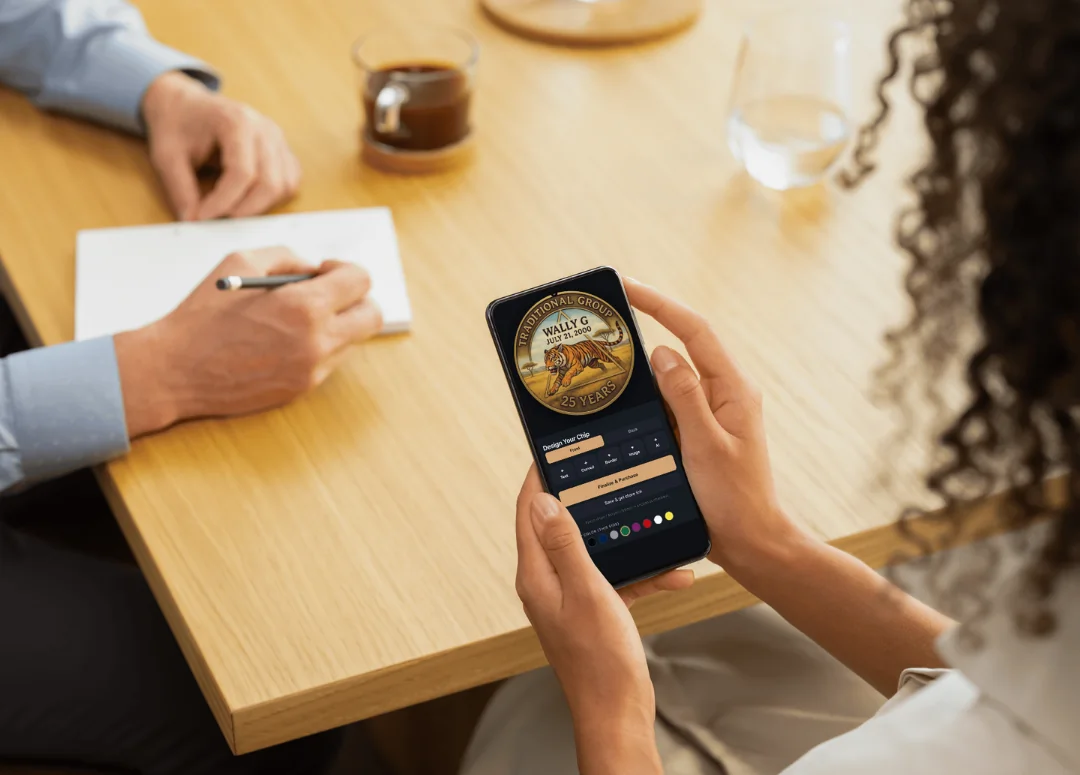 woman holds smartphone creating an AA custom sobriety chip design on chipsandmedallions.com while sitting at a table in a cafe